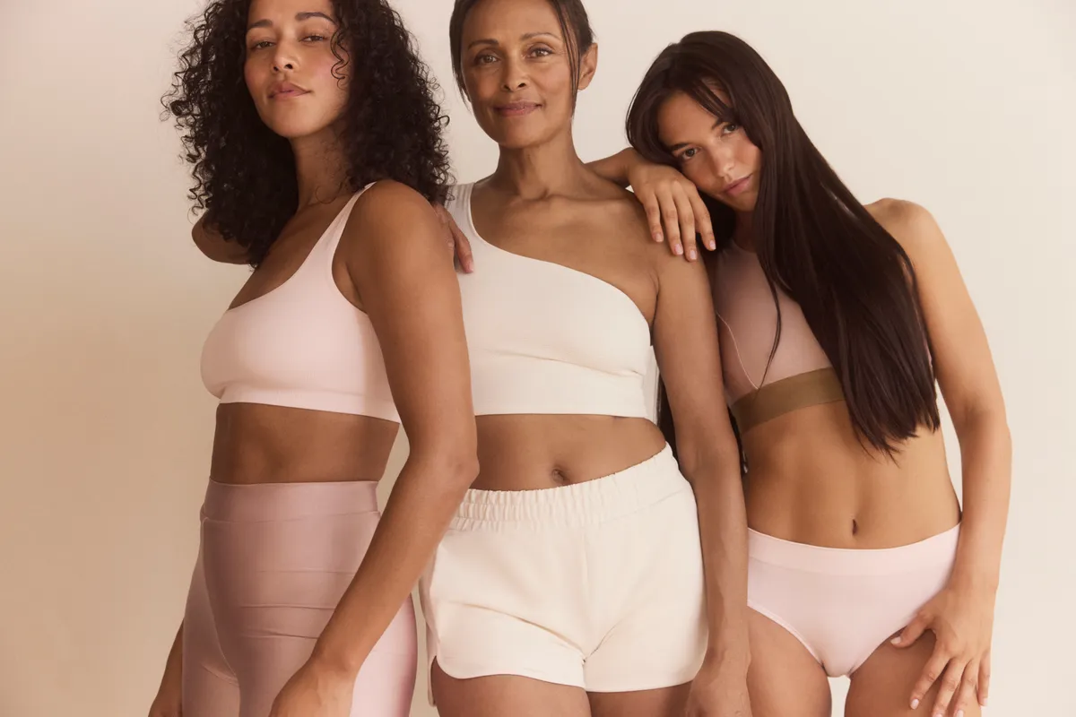 Three women posing together in a wellness lifestyle portrait.